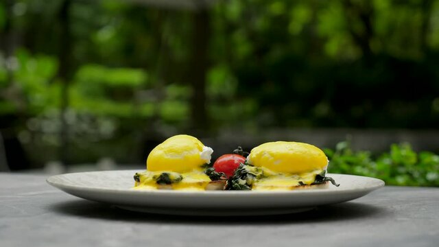 Healthy breakfast. Eggs Benedict on muffin buns with green spinach and vegetables. Two poached eggs with yellow hollandaise yolk sauce. Traditional English breakfast in luxury hotel, restaurant