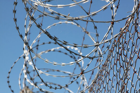 Prision. arbed wire. Wire fence. Jail. Confinement. Security. Restricted access to enter or exit. Metal fence. Enclosure.
