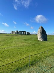 stonehenge at midday with blues sky and green grass