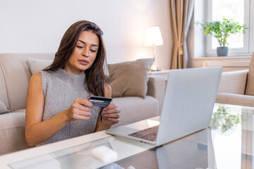 Beautiful girl using laptop computer at home. Online shopping concept. The cashless way is the convenient way. Shot of a young woman using a laptop and credit card on the floor at home