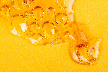 drop of amber cannabis wax, medical concentrate of marijuana on a yellow background close-up