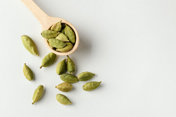 Top view of fragrant oriental spices cardamom pods with seeds in  wooden spoon with copy space
