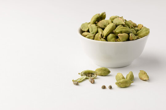 Fragrant oriental spices cardamom pods with seeds in a small white ceramic boul with copy space