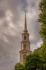 Fototapeta na wymiar 2021-10-30 AN OLD CHURCH STEEPLE IN BOSTON MASSACHUSETTS WITH CLOUDY SKYS AND GREEN TREES