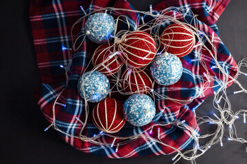 Christmas round handmade toys lie on a plaid blanket with garlands