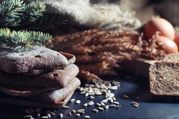 Fresh loaves of bread with wheat and gluten on a black table. Bakery and grocery concept. Fresh, healthy sorts of rye and white loaves food closeup. Fresh homemade bread with cereals.