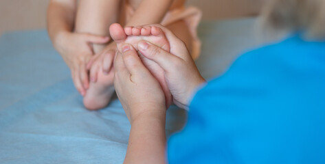 Little baby feet in the hands of the masseur. Close-up. Massotherapy. Copyspace.