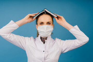 Young beautiful doctor woman in lab coat, studio shot, blue background