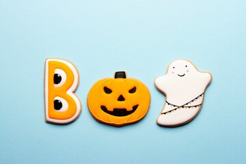 Homemade Halloween cookies in the shape of the word Boo with a pumpkin and ghosts on a blue background