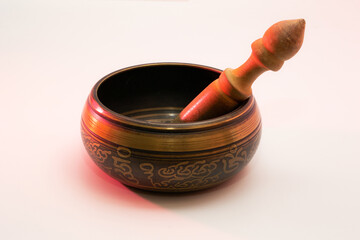 Photo of tibetan singing metal bowl for meditation with ringing stick inside on white background lit with red light  - obrazy, fototapety, plakaty