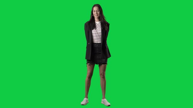 Stylish woman with hands behind back giving and offering invisible empty hand gift as surprise. Full body isolated on green screen background
