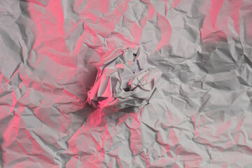 wrapped wrinkled white Paper ball made of office paper on crumpled paper background lit with red light
