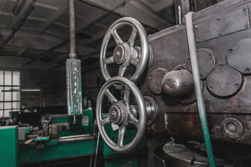 Iron round handles of the old milling machine of equipment and tools for metal processing in the workshop of the industrial plant