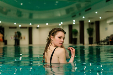 Portrait of beautiful woman in swimwear relaxing in swimming pool spa.