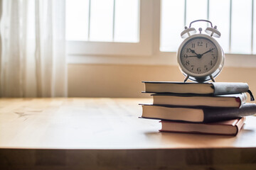 Stack Of Books And an Alarm Clock On The Wooden Table
