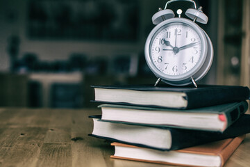 Stack Of Books And an Alarm Clock On The Wooden Table