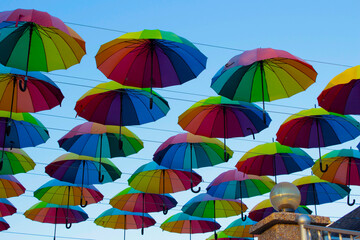 Fototapeta na wymiar Many colorful umbrellas hang in the sky above the cafe. Decorating the street with umbrellas.