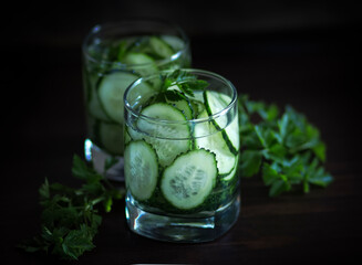 Nutritious detoxification water with cucumber in glasses on a dark background