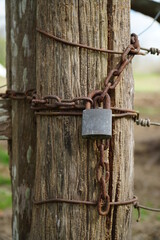 Candado y cadena oxidados cerrando una puerta en el campo
