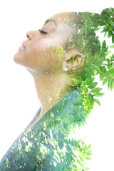 Fototapeta premium A profile portrait of a woman dissolving into green twigs. Double exposure technique.