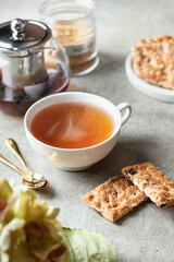 Hot steamed tea and cookies on green background