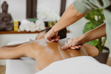 Obraz na płótnie Canvas African American woman having back massage in modern spa salon.