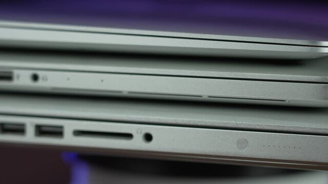 A rotating extreme closeup view of the ports on three different generations of modern laptops.  	