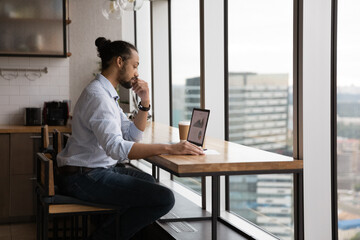 Concentrated young african american 30s businessman employee worker analyzing graphs and charts in electronic research report on computer, developing online project growth strategy in modern office.