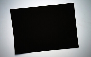 A black sheet of paper on a white isolate. Craft cardboard in black on a white table. Dark background for the text.