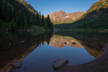 Maroon Bells, crystal clear Maroon Lake and beautiful summer reflections in early morning near Aspen, Colorado
