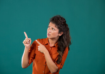 Girl showing on empty space with disbelief in studio