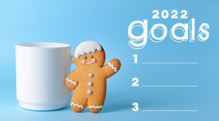 Cup with cookie and empty to do list for 2022 year on color background