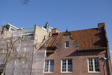 Renovation of a new, modern building together with an old building with a clock gable in the Dutch city of Alkmaar. October, autumn, Netherlands. 