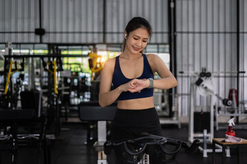 Fototapeta na wymiar Beautiful sporty woman using smart watch checking notify between sports training at gym