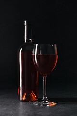 Fototapeta na wymiar Bottle and glass of red wine on black background