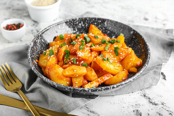 Plate with honey chilli potato on light background