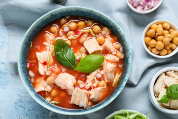 Bowl with delicious pozole soup and vegetables on color background, closeup