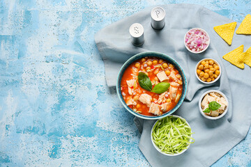 Composition with delicious homemade pozole soup and vegetables on color background