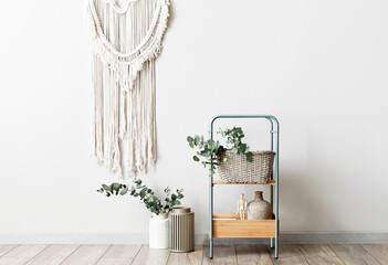 Shelving unit and eucalyptus branches near light wall