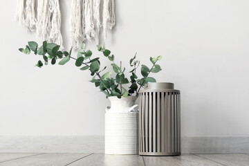 Vase with green eucalyptus branches near white wall