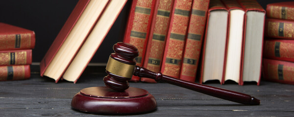 Law concept - Open law book with a wooden judges gavel on table in a courtroom or law enforcement...