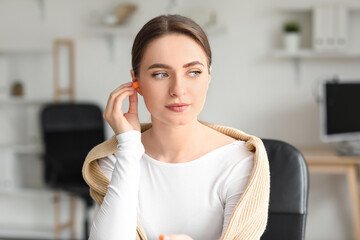 Young woman with earplugs working in office