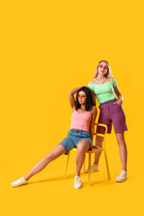 Fashionable young women on color background