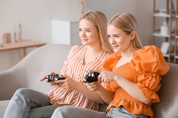 Young twin sisters playing video game at home