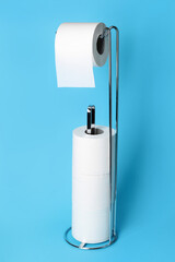 Modern holder with toilet paper rolls on blue background