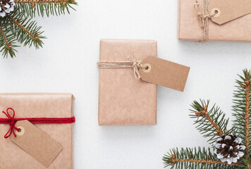 Gift boxes behind green branches. Blank tag for text space. Holiday background with a Christmas presents. Flat lay.	
