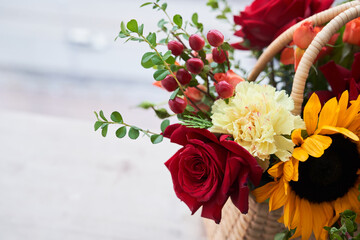 Close-up of a basket with beautiful autumn flowers made of red roses, sunflowers and green leaves. The concept of the holiday. Copy space. High quality photo