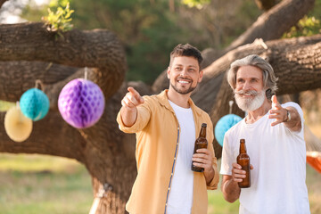 Happy man and his father drinking beer at barbecue party on summer day