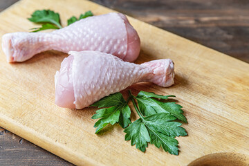 fresh raw chicken legs decorated with parsley on a cutting board