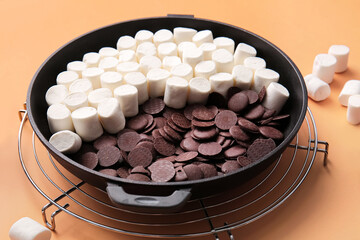 Frying pan with uncooked S'mores dip on color background, closeup